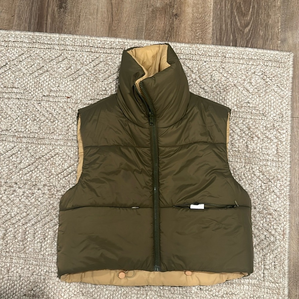 Cropped vest. Olive green outside with 2 small zip pockets